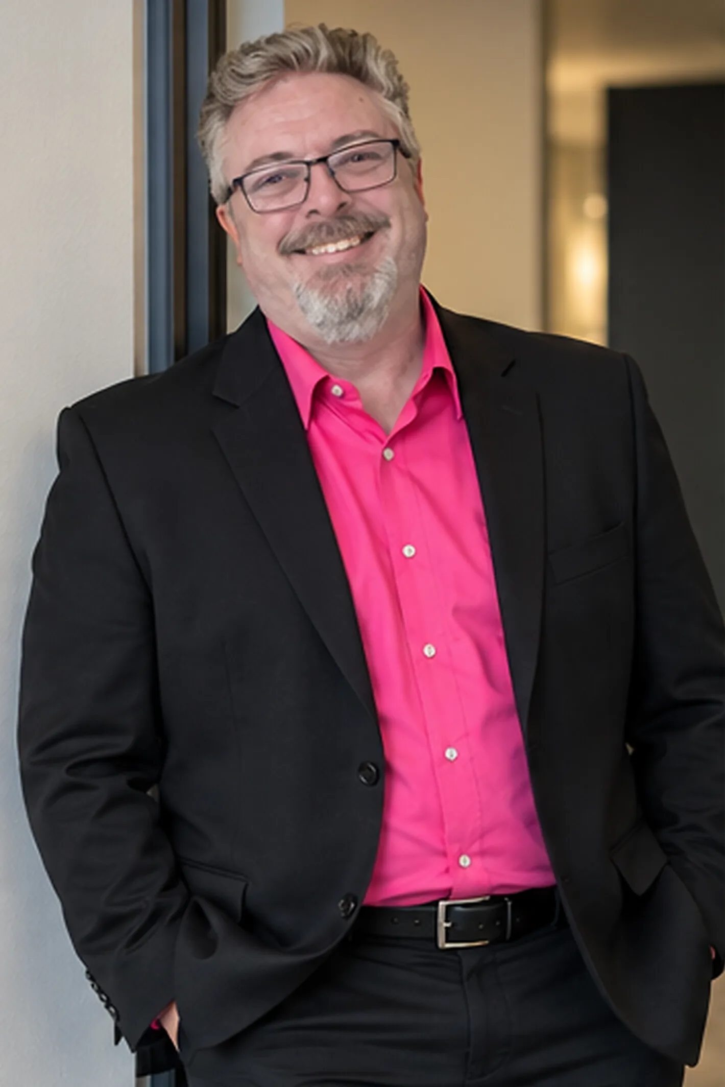 Corey Frasure standing, black jacket, pink shirt